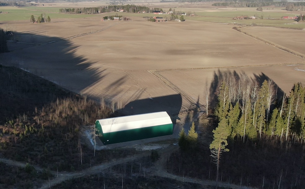 En grön maskinhall med vitt tak ute på landsbygden utanför Hedemora.
