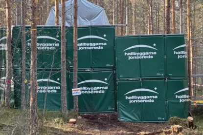Bullermattor som täcker av och skyddar ett närliggande bostadsområde från buller under ett borrprojekt i skogen.
