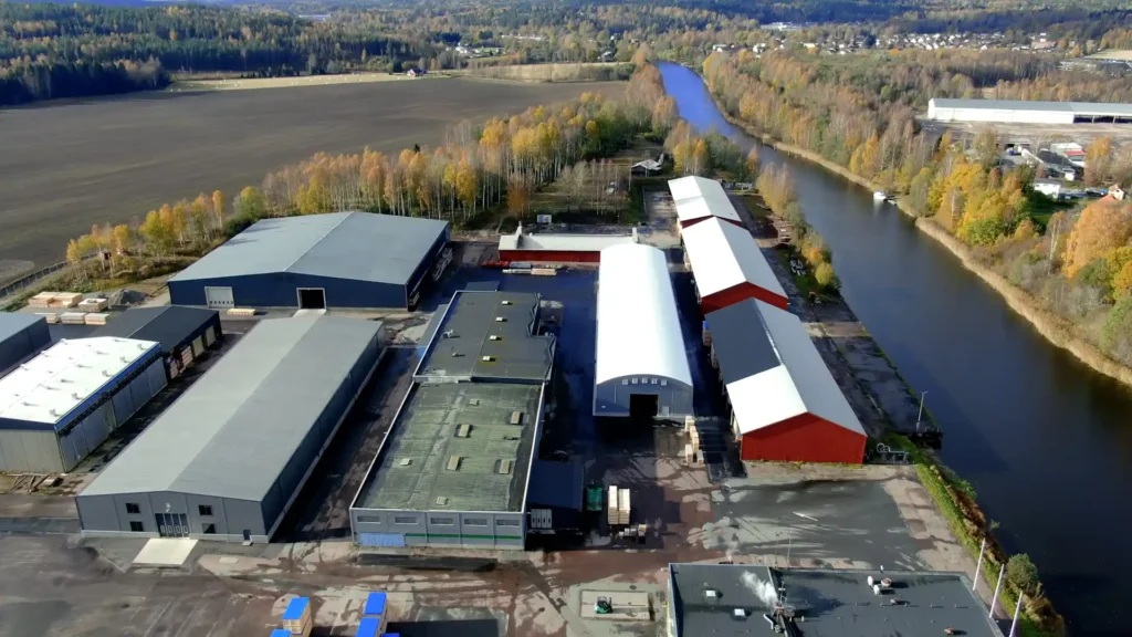 Industrihallar hos Wermland Logistikcenter. Grå hall med vitt tak i fokus och en å som ligger bredvid industriområdet.
